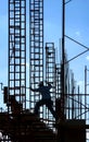 Silhouette of construction worker jumping across scaffolding among steel framing