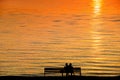 Silhouette of a couple on a bench at sunset against romantic ora Royalty Free Stock Photo