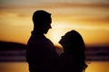 Silhouette couple enjoying romantic moment standing face to face looking into eyes at sunset. Unknown boyfriend and