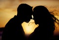 Silhouette couple enjoying romantic moment with their foreheads touching against sunset background. Unknown boyfriend