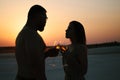 Silhouette of a couple with glasses on sunset background, man and woman clanging wine glasses with champagne at sunset dramatic sk Royalty Free Stock Photo