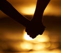 Silhouette of a couple holding hands on the beach. Closeup on hands of couple holding hands at sunset on the beach Royalty Free Stock Photo