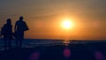 silhouette of a couple holding hands and looking at the sea on the beach during sunset Royalty Free Stock Photo