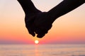 Silhouette of couple holding hands at sunset on the beach Royalty Free Stock Photo