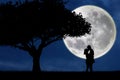 Silhouette of couple kissing on blue full moon