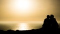 Silhouette of a couple kissing while sitting near a beautiful sea - great for a background