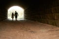 Silhouette of a couple in love, holding hands, walking towards the light from the tunnel Royalty Free Stock Photo