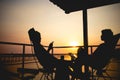 Silhouette of couple lover sitting and relax on romantic sunset at the sea of honeymoon vacation. Royalty Free Stock Photo