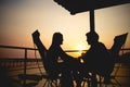 Silhouette of couple lover sitting and relax on romantic sunset at the sea of honeymoon vacation. Royalty Free Stock Photo