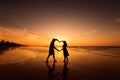 Silhouette of couple making heart shape with arms on beach at sunset Royalty Free Stock Photo