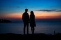 Silhouette of couple man and woman in front of twilight sunset. Dark colors sky beautiful sea sunset. Two people in Royalty Free Stock Photo