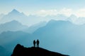 Silhouette Couple of man and woman reaching mountain top enjoying freedom and looking towards blue mountain silhouettes Royalty Free Stock Photo