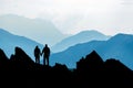 Silhouette Couple of man and woman reaching mountain top enjoying freedom and looking towards blue mountain silhouettes Royalty Free Stock Photo