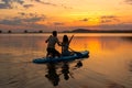 silhouette of couple paddleboarding at lake during sunset together