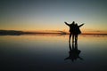 Silhouette of a couple raising their arms for the happy moment on the incredible mirror effect of Uyuni Salt Flats, Bolivia Royalty Free Stock Photo