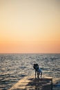 Silhouette of couple standing and kissing at the pier, watching the sunrise at the beach summer time Royalty Free Stock Photo