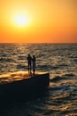 Silhouette of couple standing at the pier, watching the sunrise at the beach summer time Royalty Free Stock Photo