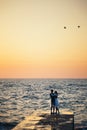 Silhouette of couple standing at the pier, watching the sunrise at the beach summer time Royalty Free Stock Photo