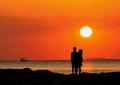 Silhouette of couple standing by the sea watching the sunset. Royalty Free Stock Photo