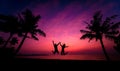 Silhouette of couple on tropical beach during sunset on background of palms