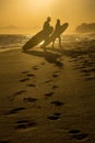 Silhouette of a couple walking along the beach with surfboards d Royalty Free Stock Photo