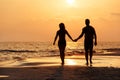 Silhouette of a couple walking at the beach in front of the sunset Royalty Free Stock Photo