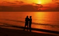 Silhouette of a couple walking on the beach at sunset. Royalty Free Stock Photo