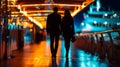Silhouette of a couple walking on a brightly lit walkway at night Royalty Free Stock Photo