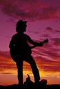Silhouette of a cowboy foot on saddle playing guitar