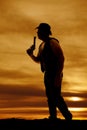 Silhouette of a cowboy with a pistol blow in sunset
