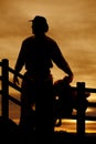 Silhouette cowboy saddle in front of fence