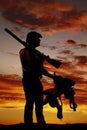 Silhouette of a cowboy in the sunset holding a gun over shoulder