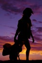 Silhouette of a cowgirl holding a saddle behind her