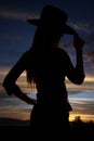 Silhouette of cowgirl tipping her hat at sunset Royalty Free Stock Photo