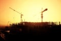 Silhouette of a crane and frame of a building under construction at sunset background Royalty Free Stock Photo