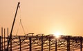 Silhouette crane lifting castellated beam to installing on large industrial building structure in construction site at sunset Royalty Free Stock Photo