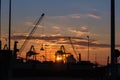 Silhouette of Cranes at Work in Boatyard at Sunset