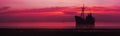 Silhouette of a crashed ship in sea. Sunset over the sea. Panorama