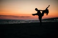 Silhouette of a crazy couple posing on a beach with a background of beautiful sunset.