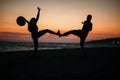 Silhouette of a crazy couple posing on a beach with a background of beautiful sunset.