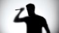 Silhouette of crazy maniac with knife standing behind glass wall, thriller