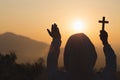 Silhouette the cross in hands, religion symbol in light and landscape over a sunrise, background, religious, faith concept Royalty Free Stock Photo