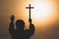 Silhouette the cross in hands, religion symbol in light and landscape over a sunrise, background, religious, faith concept Royalty Free Stock Photo