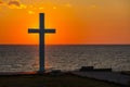 Silhouette of cross at sunrise or sunset with light rays and sea panorama Royalty Free Stock Photo