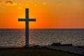 Silhouette of cross at sunrise or sunset with light rays and sea panorama Royalty Free Stock Photo