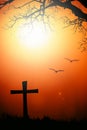 Silhouette of the cross and tree with blurred bird with flare at