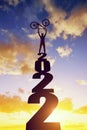 Silhouette of a cyclist with a bicycle standing on the number 2022 at sunset.