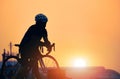 Silhouette cyclist on bike taking break and relaxing at harbor in sunset time