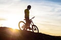 Silhouette of Cyclist in Helmet Standing with Mountain Bike on Rock at Sunset. Extreme Sport Concept. Royalty Free Stock Photo