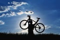 Silhouette of a cyclist with a raised bike in the grass in the sun Royalty Free Stock Photo